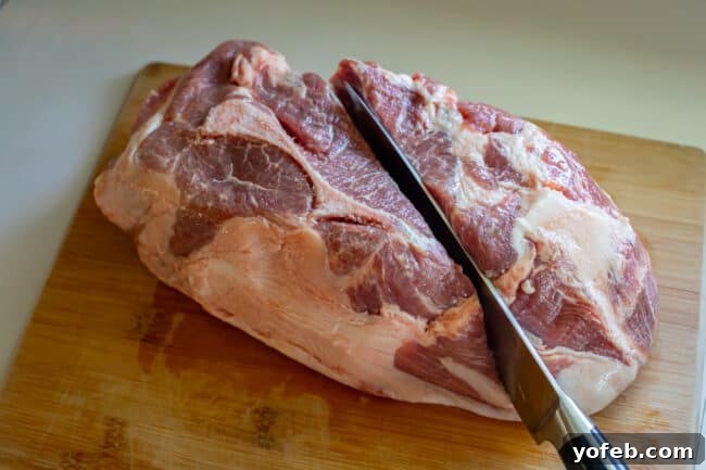 Melt In Your Mouth Pulled Pork Slow Cooker Or Oven 9 A chef's knife splitting a pork should in half on a cutting board.