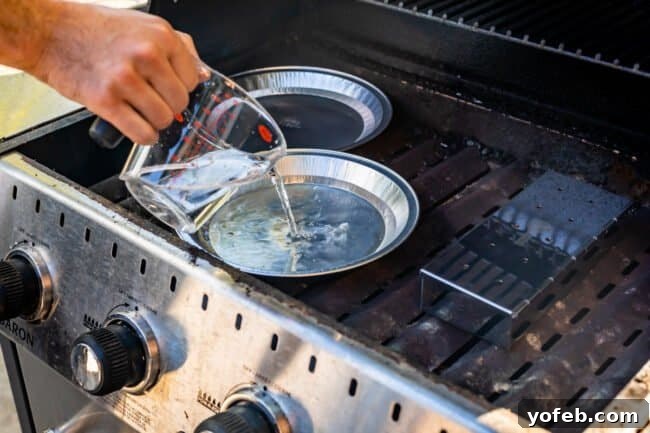 Smoky Perfection: The Ultimate Pulled Pork 16 pouring water into a tin pie pan set on the heating plates of an outdoor grill.