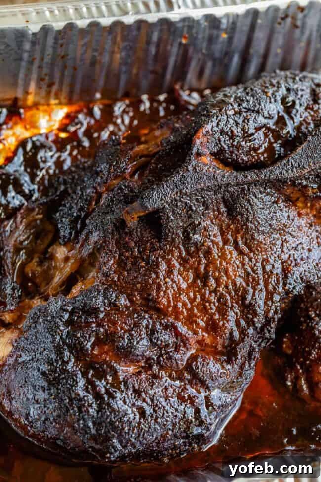 Smoky Perfection: The Ultimate Pulled Pork 22 smoked pulled pork with blackened bark crust in a aluminum pan.