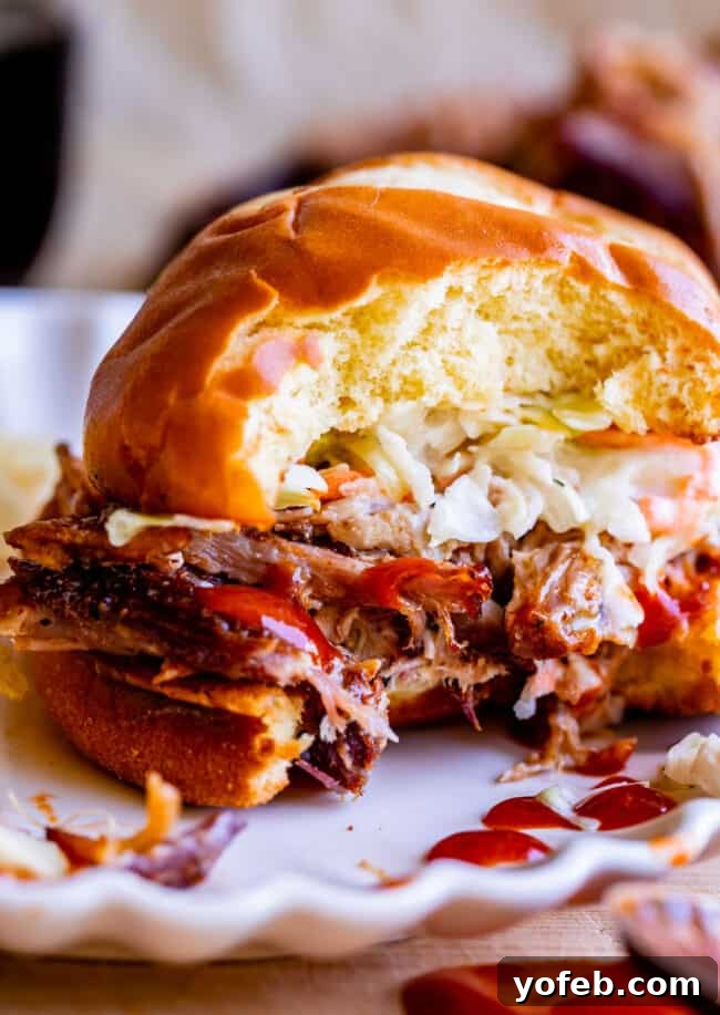 Smoky Perfection: The Ultimate Pulled Pork 5 bite taken out of smoked pulled pork sandwich with bbq sauce and coleslaw.