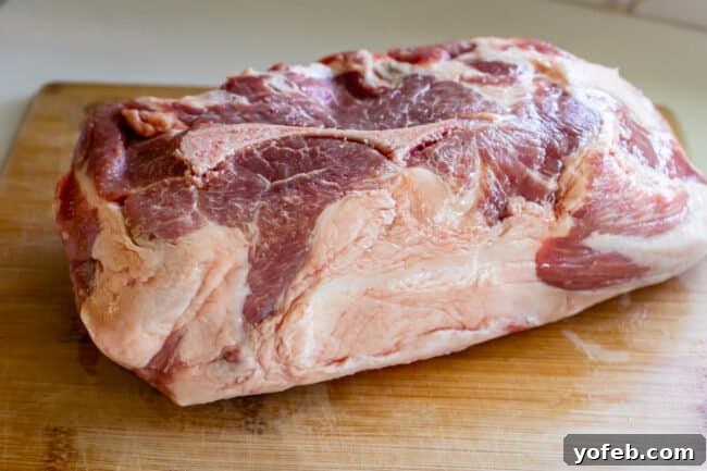 Smoky Perfection: The Ultimate Pulled Pork 7 pork shoulder with fat cap on a wooden cutting board.