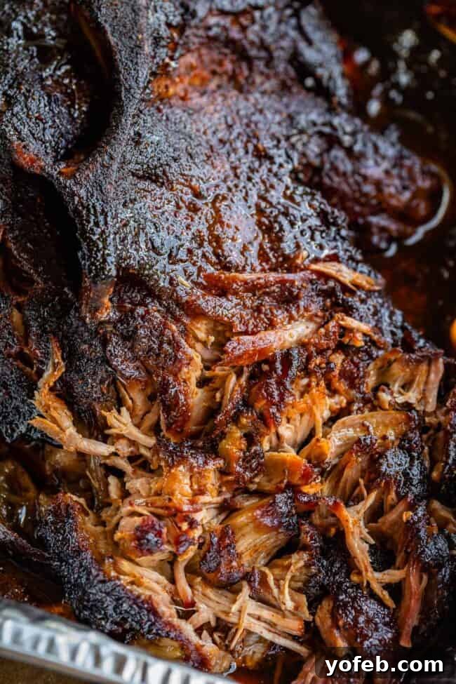 Smoky Perfection: The Ultimate Pulled Pork 9 partially shredded smoked pulled pork shoulder made on a gas grill, in an aluminum pan.