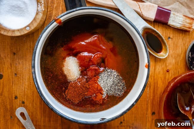 Effortless Homemade Barbecue 11 ingredients and spices for barbecue sauce in a white and black pot on a wood table.