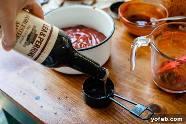 Effortless Homemade Barbecue 9 pouring worcestershire sauce into a 1/3 measuring cup on a table.