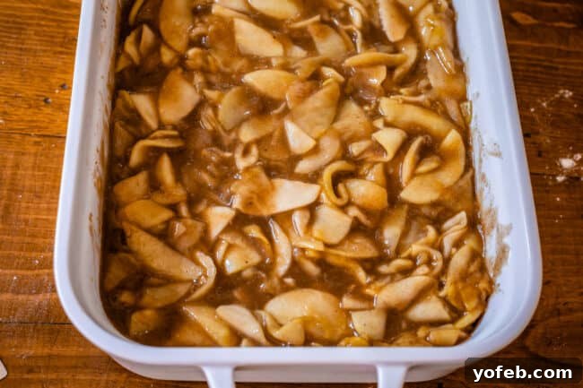 Effortless Homemade Apple Cobbler 13 Cooked, saucy apples beautifully arranged in a white casserole dish.