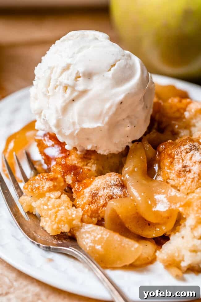 Effortless Homemade Apple Cobbler 5 Easy apple cobbler on a white plate with a fork and a scoop of vanilla ice cream.