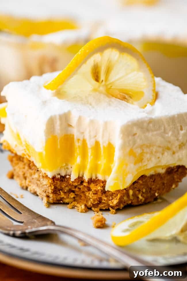 Sunshine Lemon Delight 17 A large slice of Lemon Lush Dessert with a corner removed, indicating a bite, showcasing the layered structure.