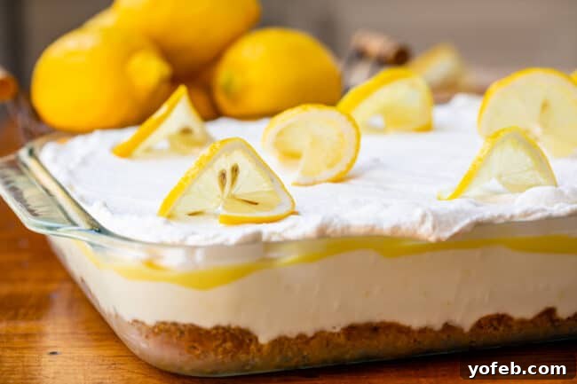 Sunshine Lemon Delight 4 Close-up of Lemon Lush Dessert topped with fresh lemon slices, highlighting its vibrant yellow and white layers.