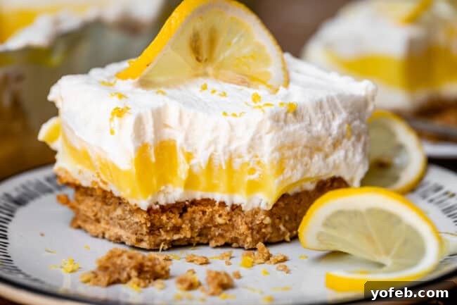 Sunshine Lemon Delight 6 A slice of lemon delight dessert on a plate, with a fork having taken a bite, surrounded by fresh lemon slices.