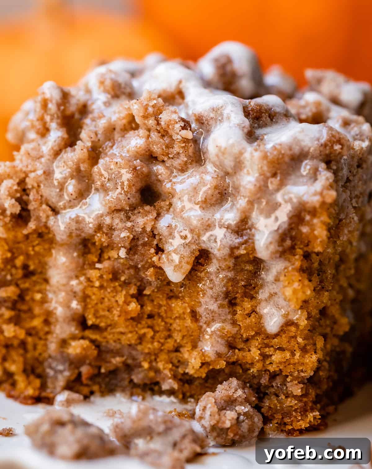 Spiced Pumpkin Crumble Coffee Cake 8 A single slice of coffee pumpkin cake on a white plate, showcasing its fluffy texture, generous streusel topping, and sweet glaze, inviting a delightful taste.