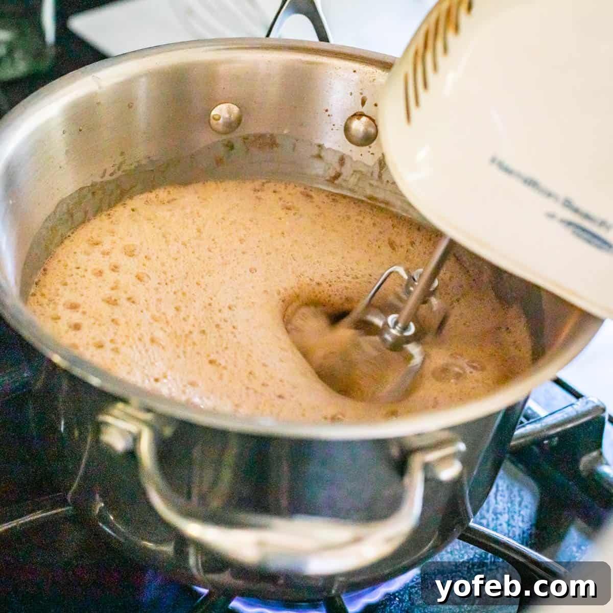 Decadent Chocolate Cream Pie Perfection 18 A hand mixer diligently beating the pudding mixture directly in a saucepan on the stovetop over medium heat, ensuring a smooth consistency.