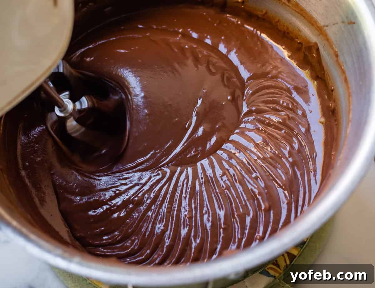 Decadent Chocolate Cream Pie Perfection 21 Chocolate pudding in a pot being beaten one last time with a hand mixer, making it extra light and fluffy.