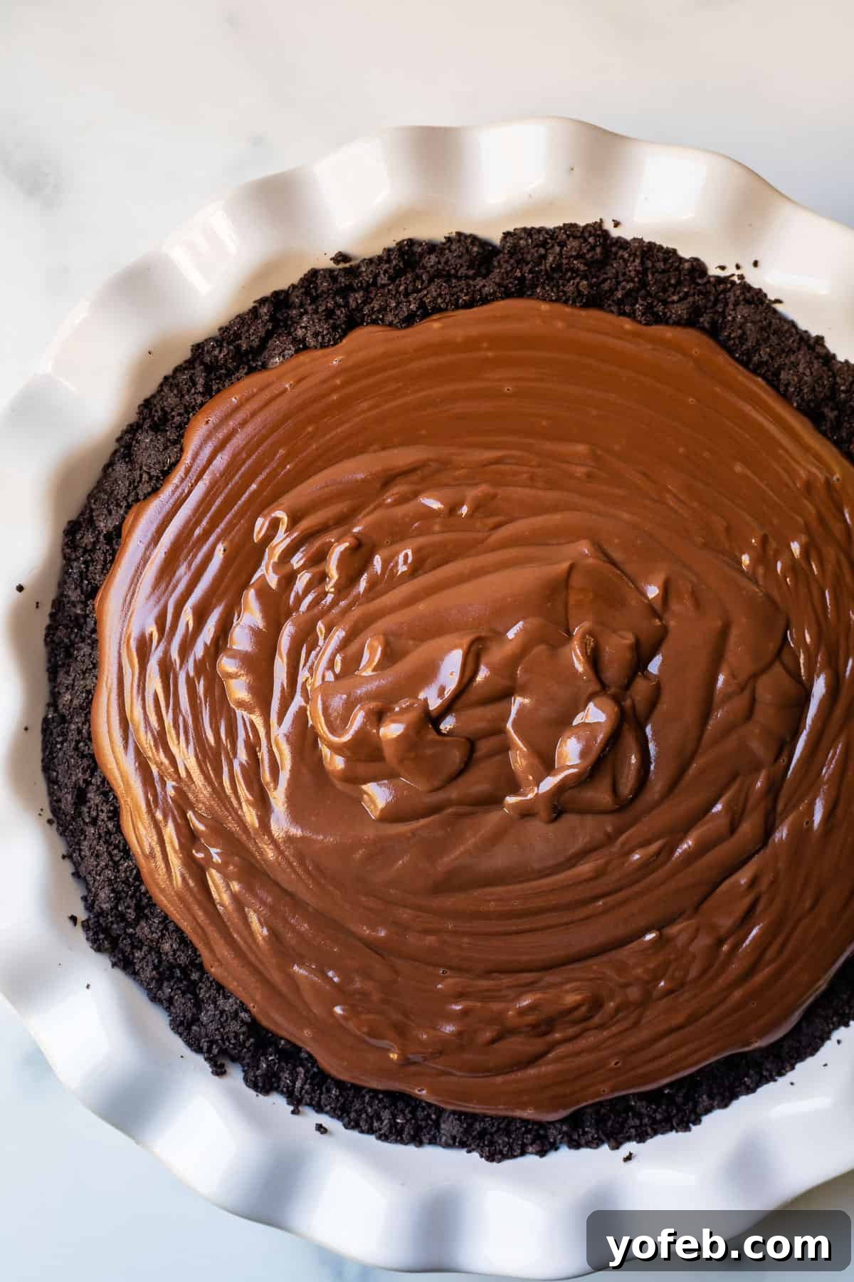 Decadent Chocolate Cream Pie Perfection 23 An overhead shot of a chocolate pudding-filled Oreo crust in a pie dish, with a smooth, dark surface.