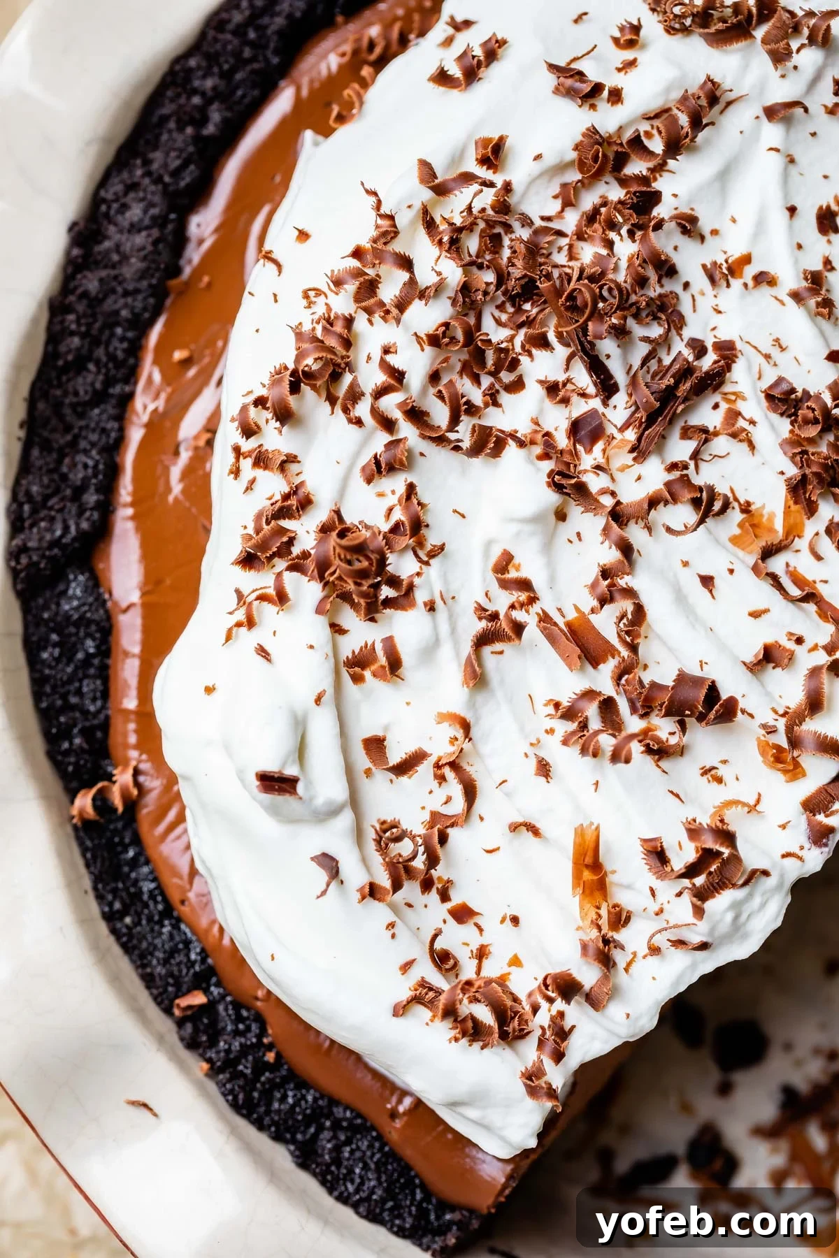 Decadent Chocolate Cream Pie Perfection 30 A beautifully topped chocolate cream pie, adorned with a cloud of whipped cream and delicate chocolate shavings, ready for serving.