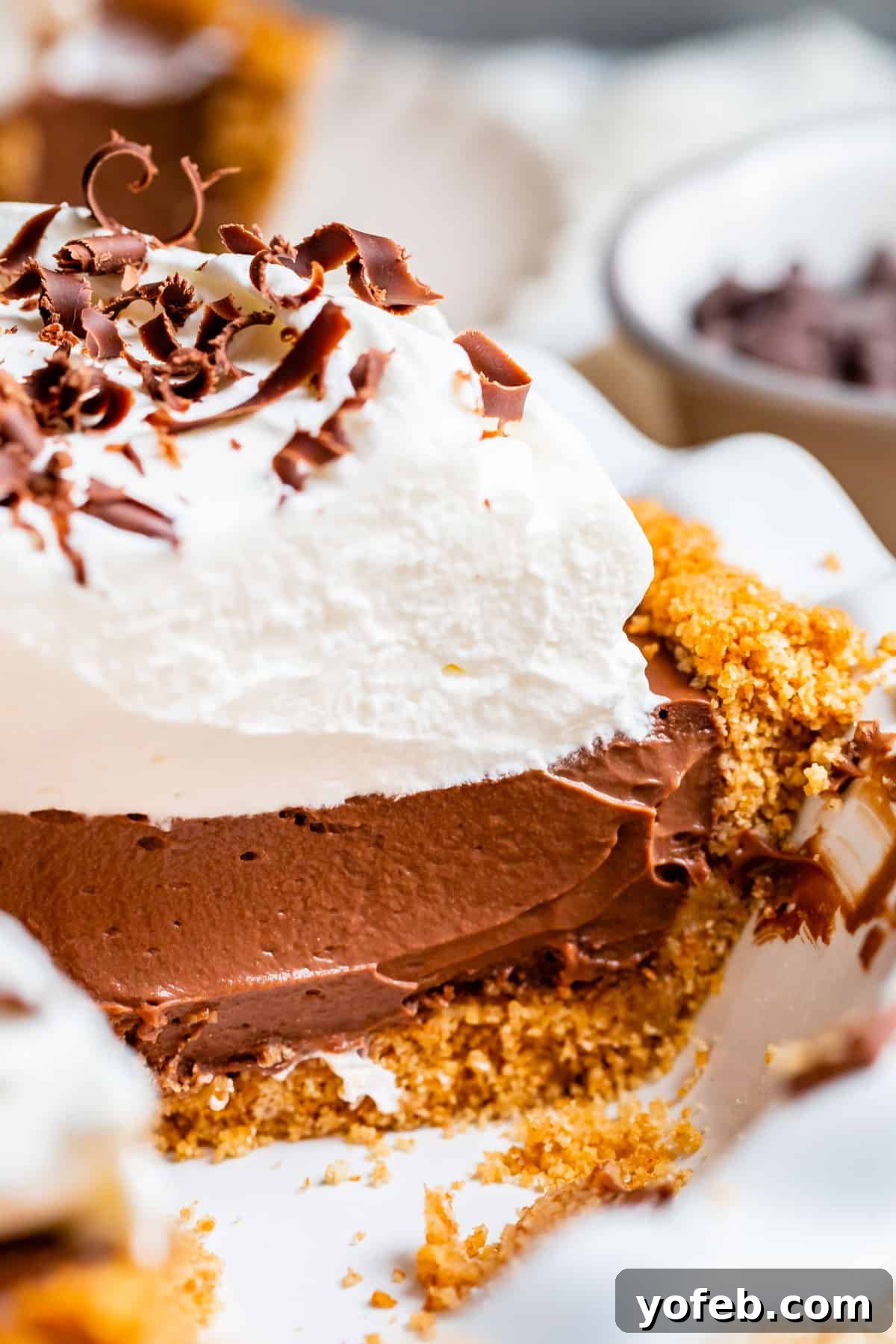 Decadent Chocolate Cream Pie Perfection 6 A stunning chocolate cream pie with a golden graham cracker crust, topped with generous whipped cream and elegant chocolate curls.