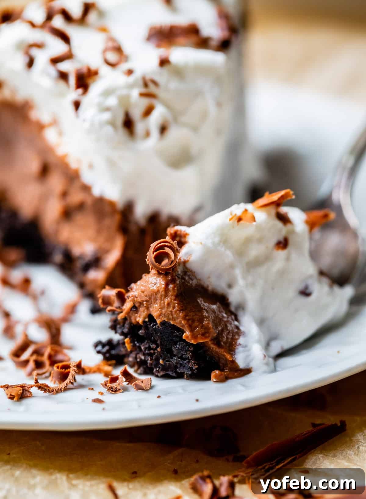 Decadent Chocolate Cream Pie Perfection 7 A fork taking a delicious bite out of a chocolate cream pie with a dark Oreo crust, showcasing its irresistible layers.
