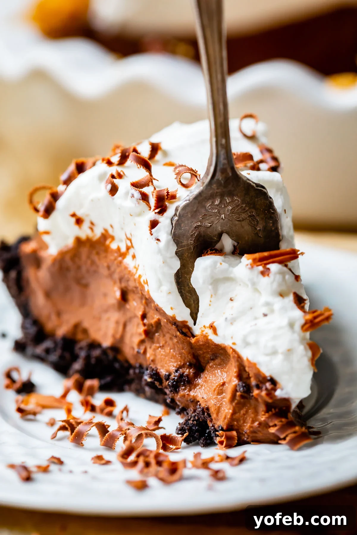 Decadent Chocolate Cream Pie Perfection 8 A perfect bite of chocolate cream pie on a white plate, showcasing the creamy filling, whipped topping, and chocolate curls.