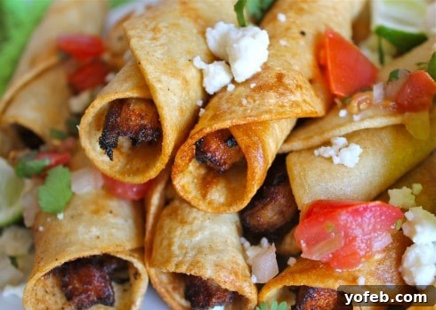 Chicken Flautas with Fresh Toppings. Deliciously crispy, easy, and authentic Mexican food. #fried #chicken #flauta #Mexican #easy #authentic #picodegallo #dinner #tortillas A vibrant close-up of homemade chicken flautas generously topped with fresh pico de gallo and crumbled queso fresco.