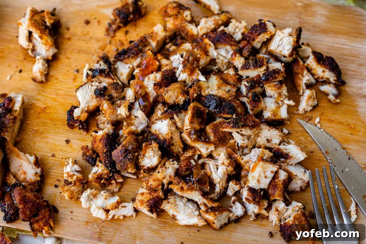 Ultimate Chicken Tacos Quick and Slow Cooker Options 10 cutting board with chopped, cooked, well seasoned chicken thigh pieces on top.