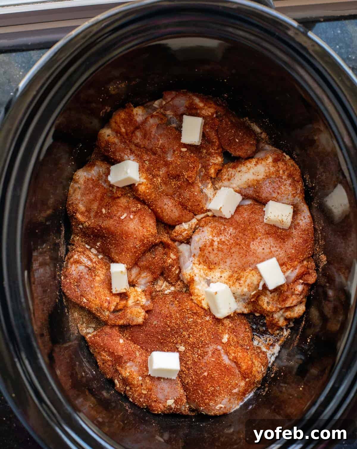 Ultimate Chicken Tacos Quick and Slow Cooker Options 11 raw chicken thighs covered in a spice dry rub sitting in a crockpot, dotted with butter.