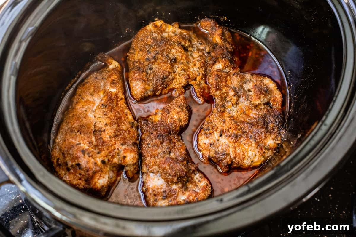 Ultimate Chicken Tacos Quick and Slow Cooker Options 12 four cooked chicken thighs in a crockpot, covered in seasonings and meat drippings.