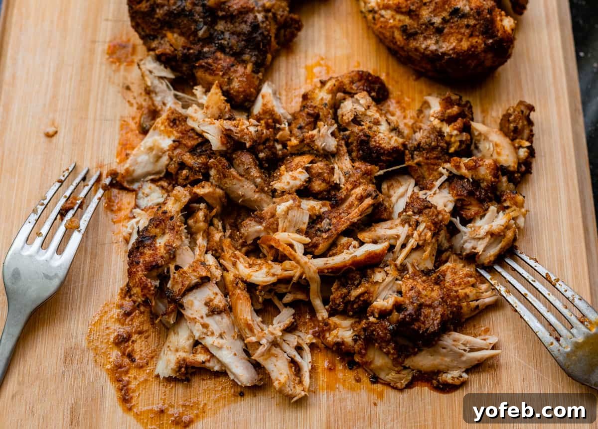 Ultimate Chicken Tacos Quick and Slow Cooker Options 14 cutting board with a pile of shredded chicken and two forks on the side that did the shredding.