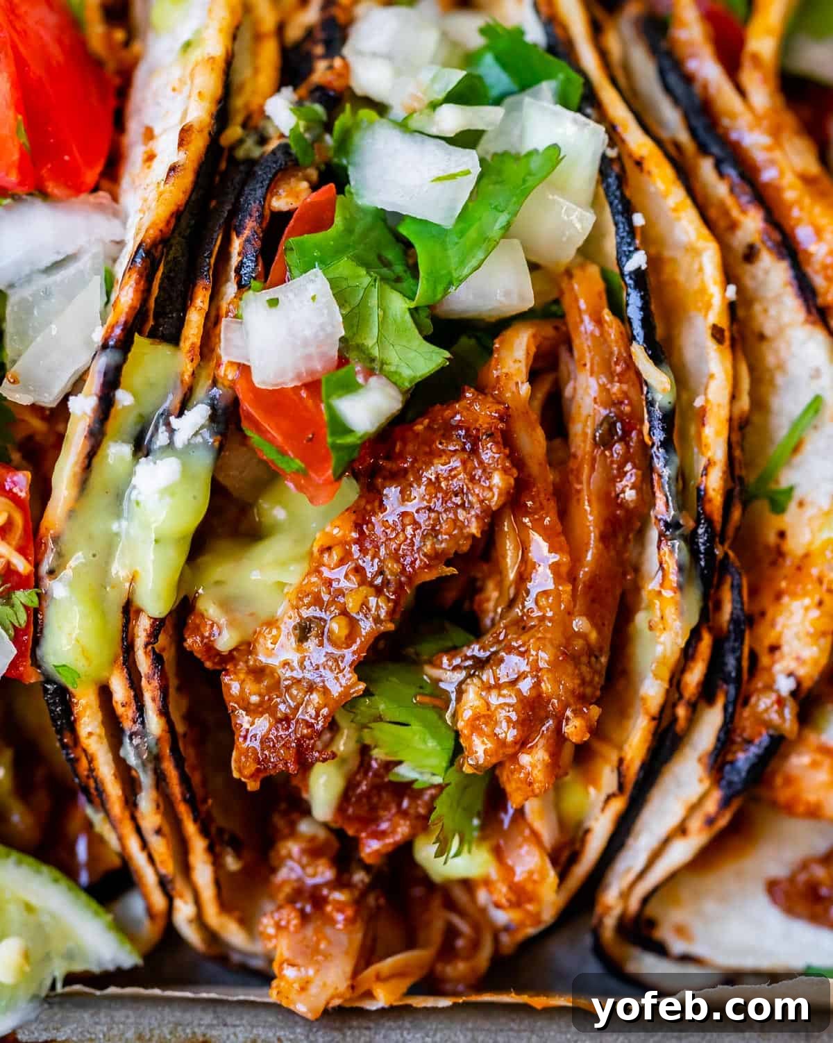 Ultimate Chicken Tacos Quick and Slow Cooker Options 18 super close up of a saucy chicken piece in a taco, with onion and cilantro on top.