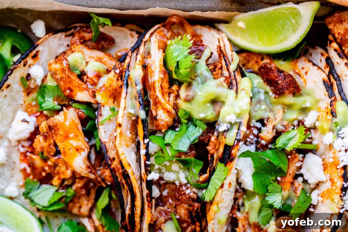 Ultimate Chicken Tacos Quick and Slow Cooker Options 19 three slow cooker chicken tacos side by side with charred tortillas, lots of saucy chicken, cilantro, and green salsa.