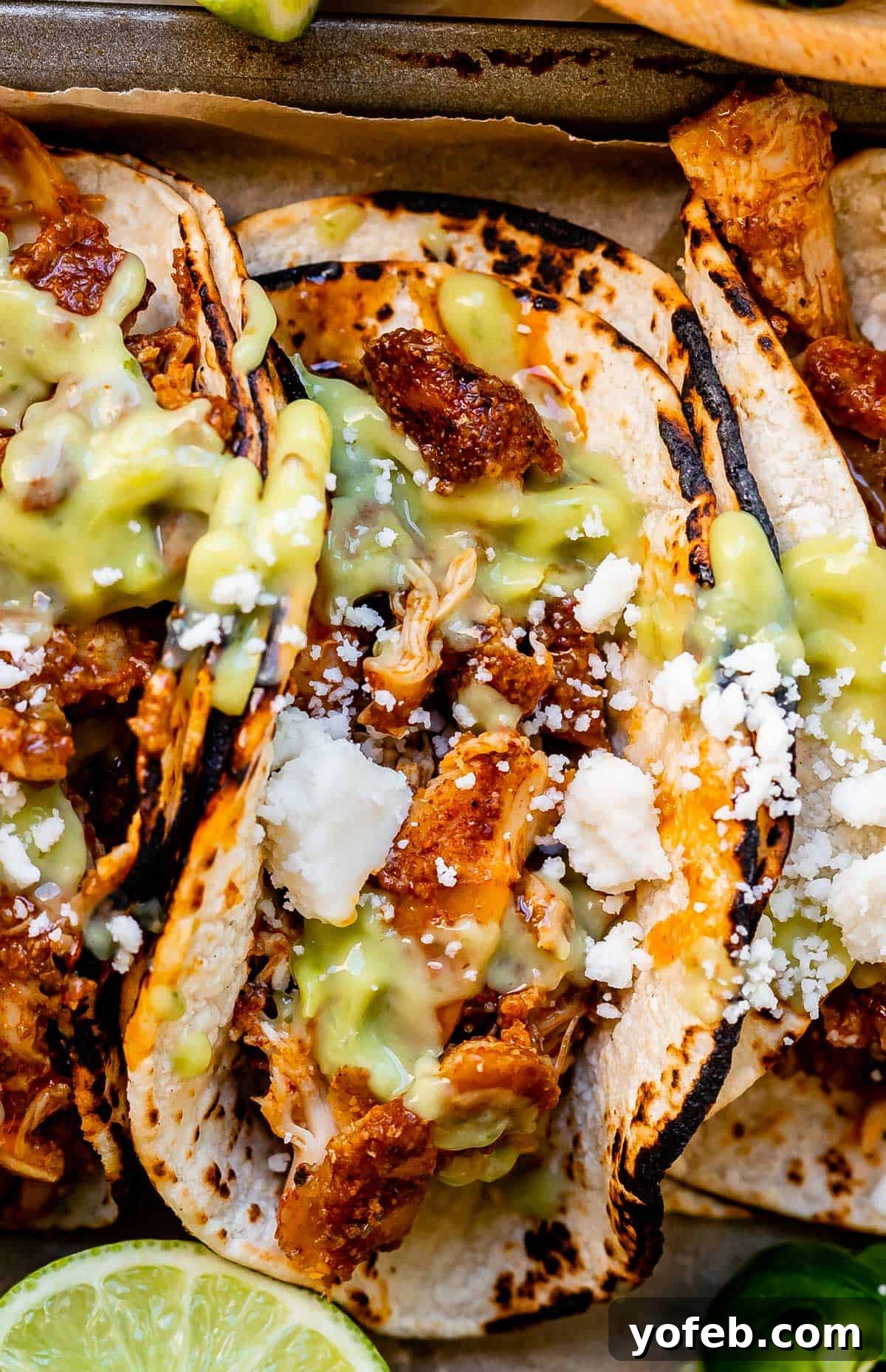 Ultimate Chicken Tacos Quick and Slow Cooker Options 3 close up of a single shredded chicken taco with juicy meat, cotija cheese, and green salsa.