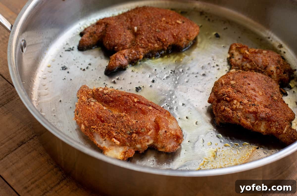 Ultimate Chicken Tacos Quick and Slow Cooker Options 8 three well seasoned chicken thighs frying in a large saute pan on the stove.