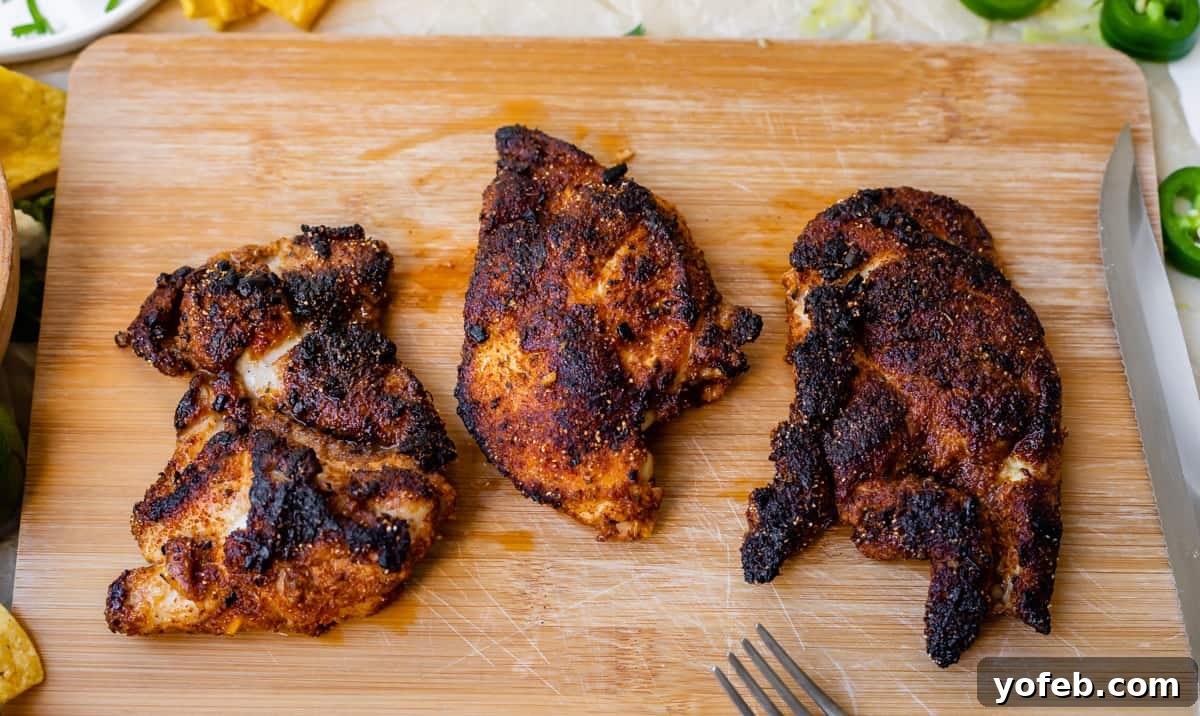 Ultimate Chicken Tacos Quick and Slow Cooker Options 9 cutting board with three well seasoned and blackened chicken thighs ready to be cut.