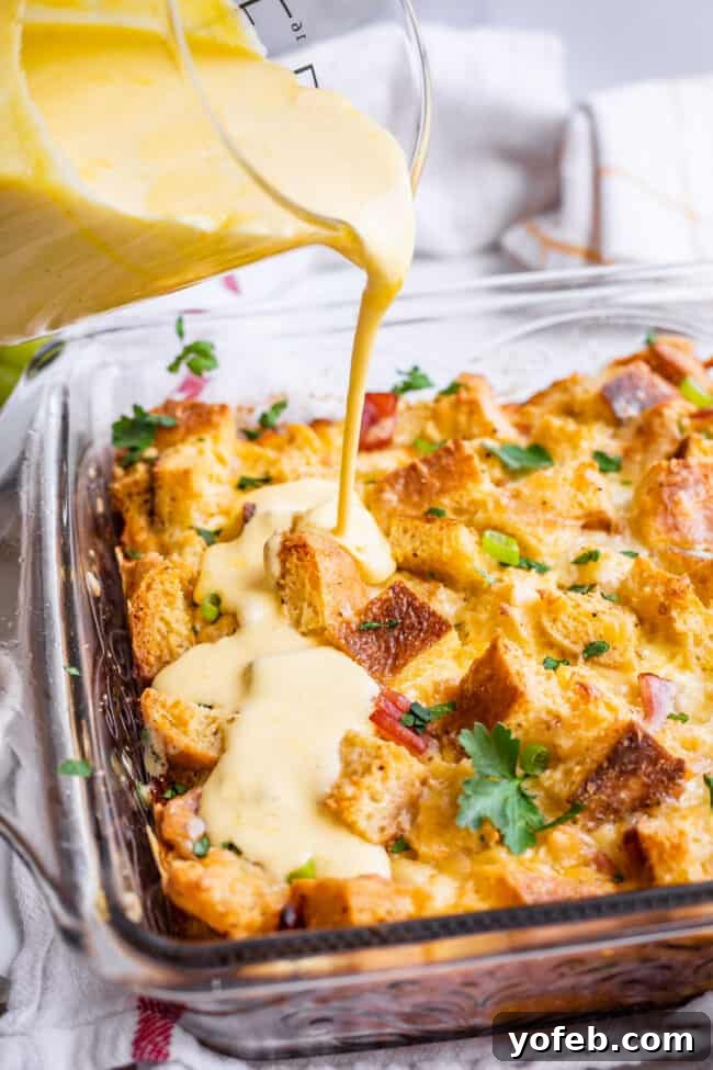 Brunch-Ready Overnight Eggs Benedict Bake 16 Pouring a generous amount of creamy hollandaise sauce over the freshly baked Eggs Benedict casserole, showing the final touch before serving.