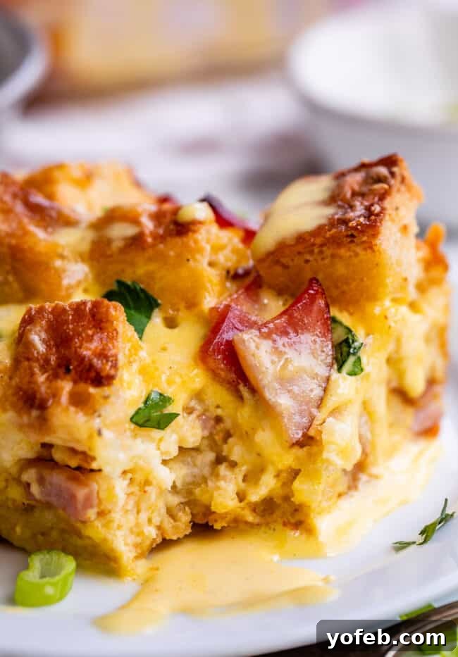 Brunch-Ready Overnight Eggs Benedict Bake 17 A serving of Eggs Benedict breakfast casserole with a generous topping of hollandaise sauce on a plate, garnished with fresh herbs, showcasing its appetizing appeal.