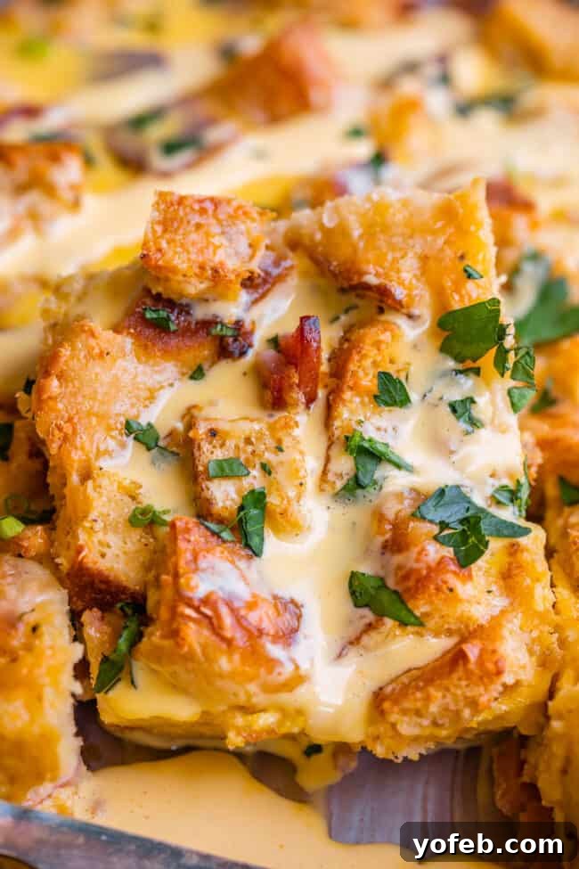 Brunch-Ready Overnight Eggs Benedict Bake 19 A perfectly cut piece of Eggs Benedict casserole, showcasing its fluffy texture and topped with rich, creamy hollandaise sauce, ready for serving.