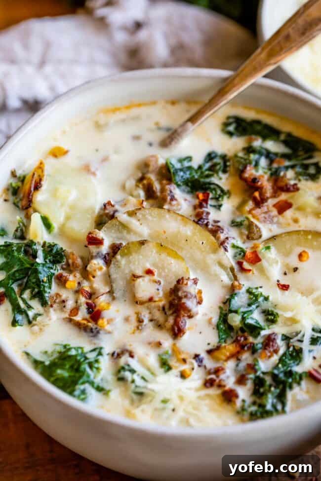 12 Restaurant Favorites You Can Make At Home 3 A steaming bowl of Zuppa Toscana soup, brimming with savory Italian sausage, tender potatoes, and vibrant kale in a creamy broth.