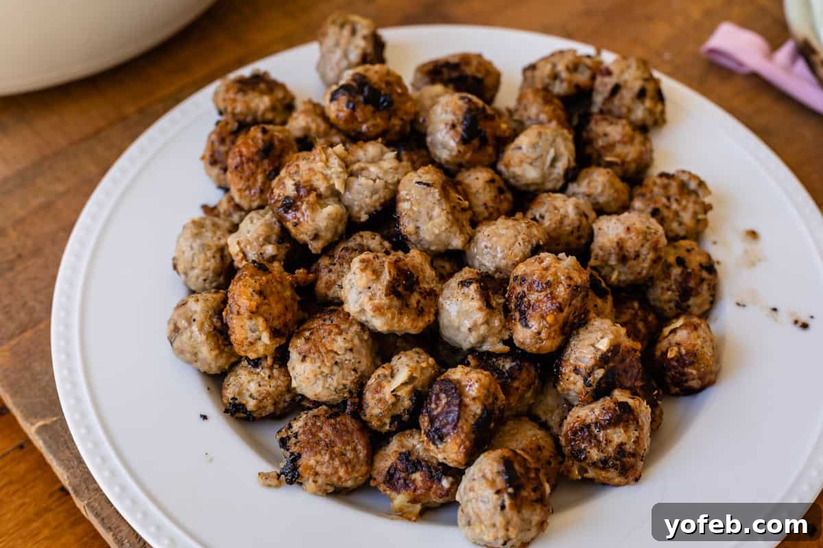 Mastering the Art of Italian Wedding Soup 14 large pile of juicy browned meatballs on a white plate.
