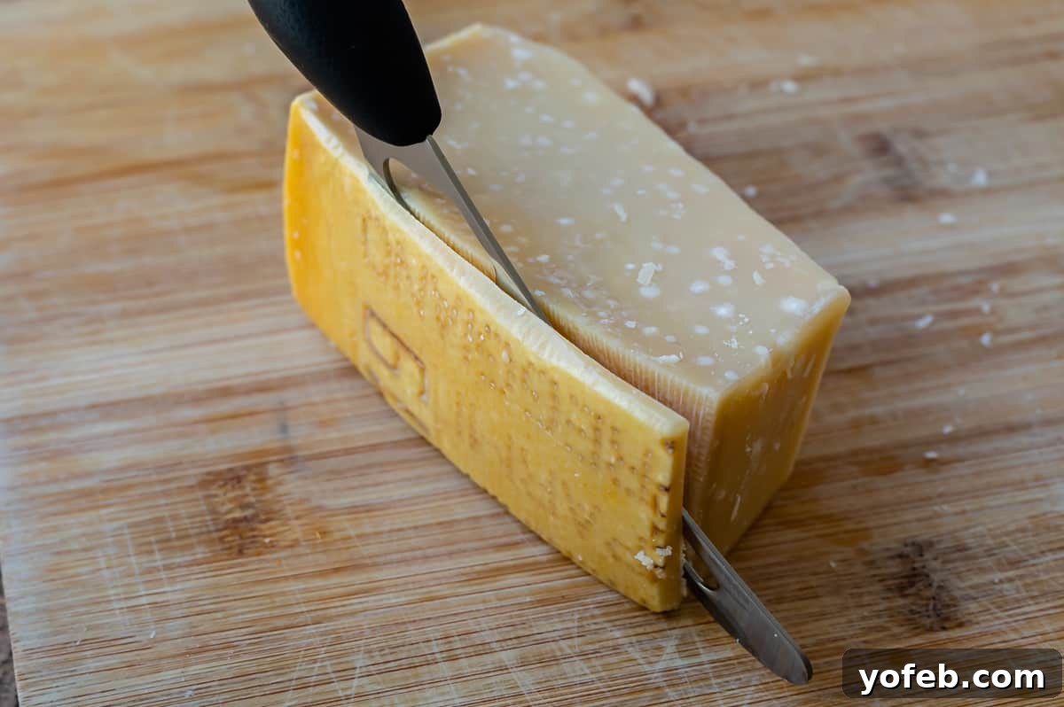 Mastering the Art of Italian Wedding Soup 18 close up of cutting the rind off a wedge of Parmesan cheese.