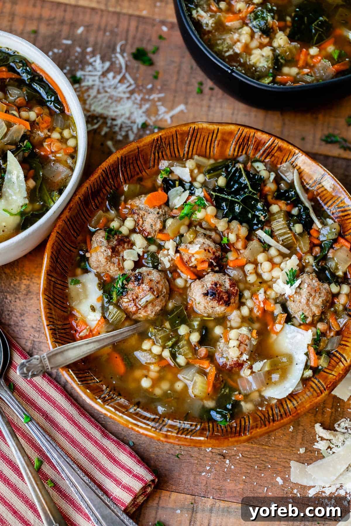 Mastering the Art of Italian Wedding Soup 3 bowls of italian wedding soup sprinkled with parmesan cheese on a wood table.