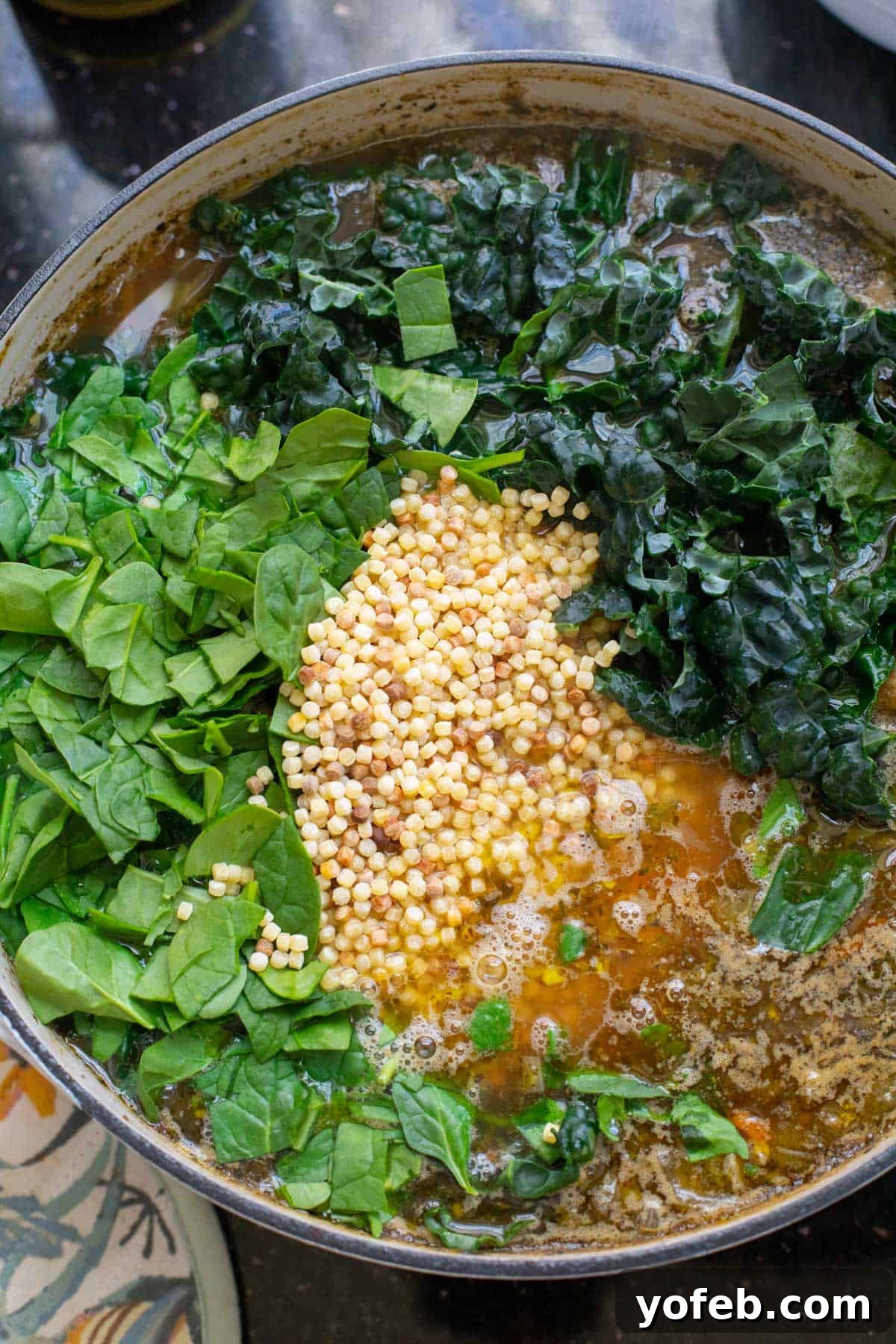 Mastering the Art of Italian Wedding Soup 23 stock pot filled with broth, spinach, kale, and tiny pasta.