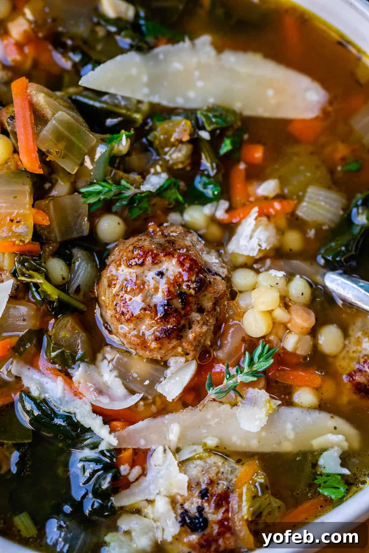 Mastering the Art of Italian Wedding Soup 4 a bowl of Italian wedding soup with meatballs, greens, parmesan, and pasta.