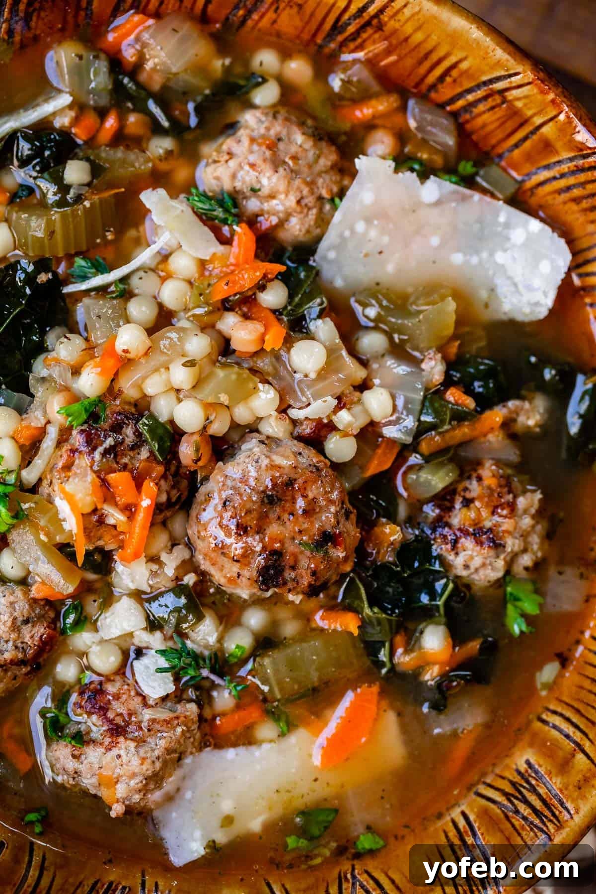 Mastering the Art of Italian Wedding Soup 8 close up of easy italian wedding soup with meatballs, pasta, greens, and broth in a brown clay bowl.