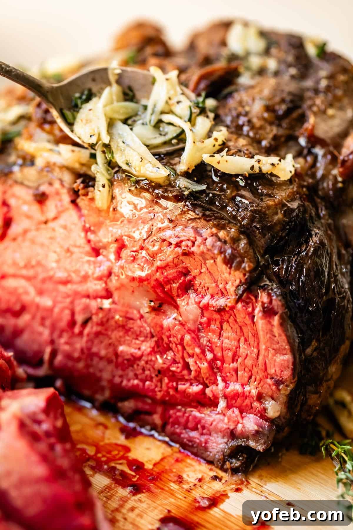 Wow Your Guests With This Perfect Prime Rib 2 Perfectly cooked cross-cut prime rib, roasted to a beautiful medium-rare, with aromatic garlic and melted butter drizzled over its crust. It sits majestically on a wooden carving board, ready to be sliced for a holiday feast.