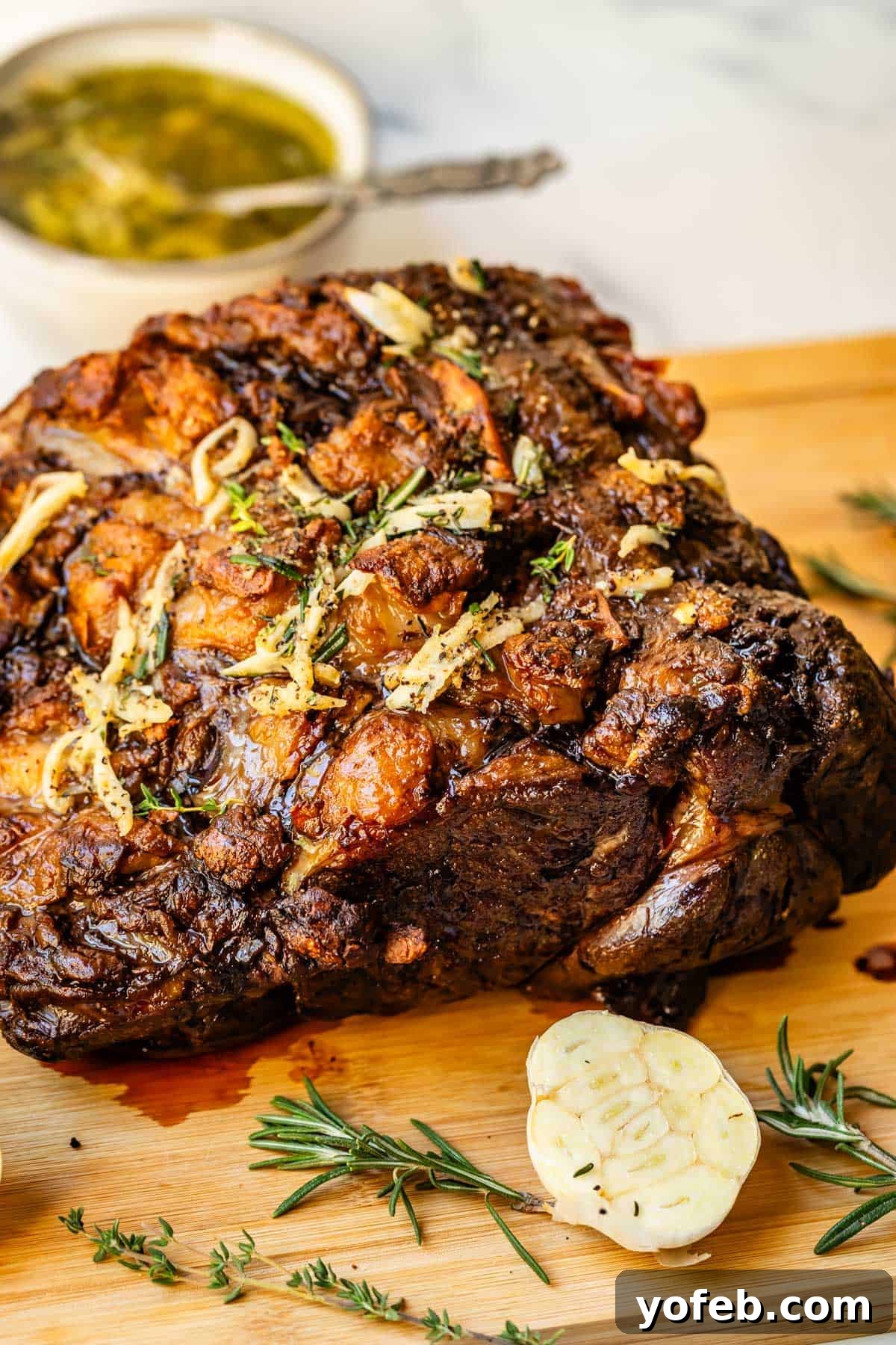 Wow Your Guests With This Perfect Prime Rib 4 A beautifully seared prime rib roast, golden brown on the exterior, rests on a cutting board, with thinly sliced garlic cloves scattered in the foreground, promising rich flavor.