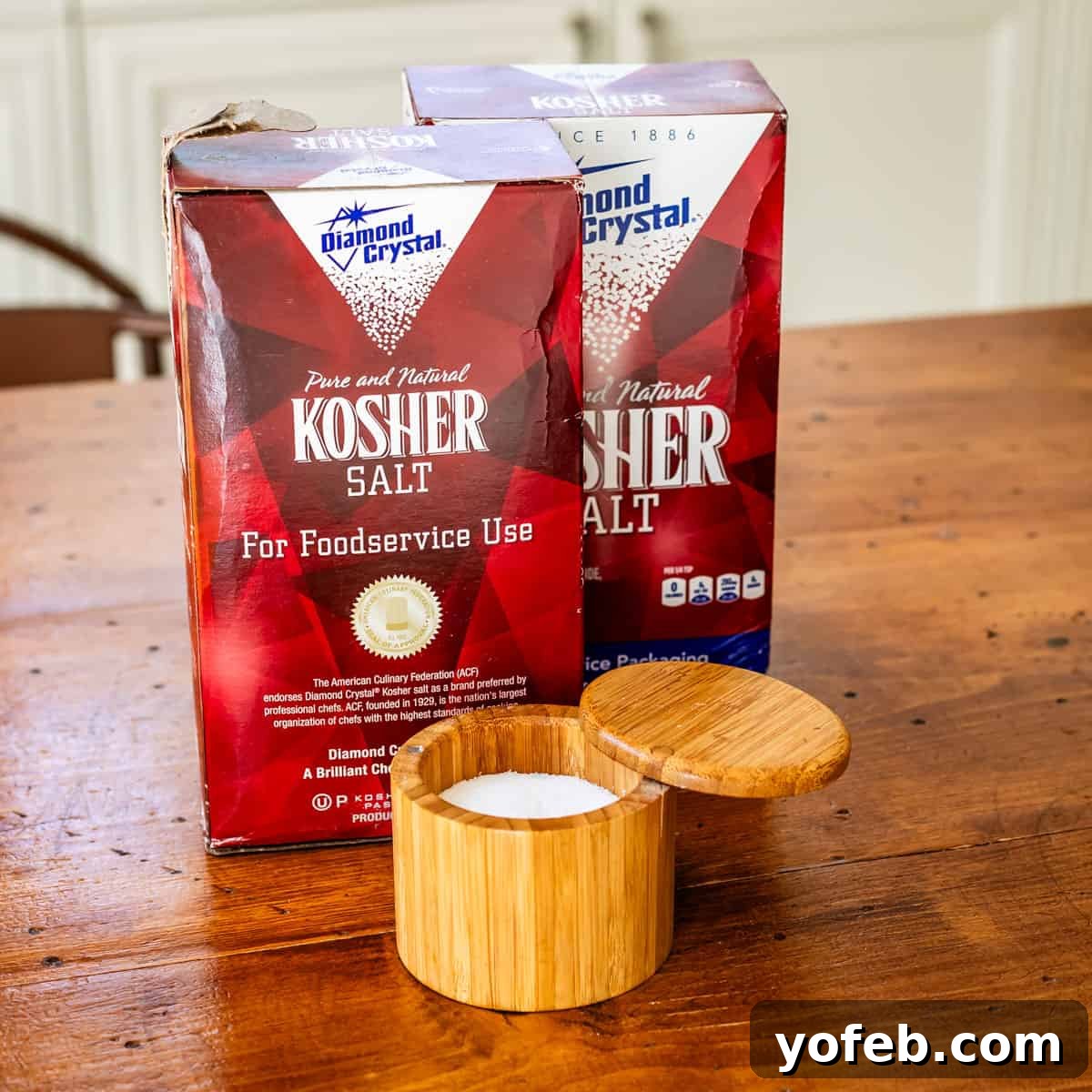 Wow Your Guests With This Perfect Prime Rib 7 Diamond Crystal kosher salt boxes neatly stacked, with an open container of the salt on a rustic wooden table, ready for cooking.