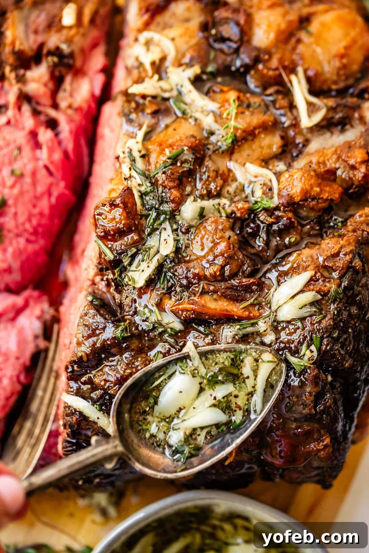 Wow Your Guests With This Perfect Prime Rib 8 A skilled hand carefully spoons fragrant garlic and herb butter over a beautifully roasted beef, ensuring every part is coated with the rich, melted goodness.