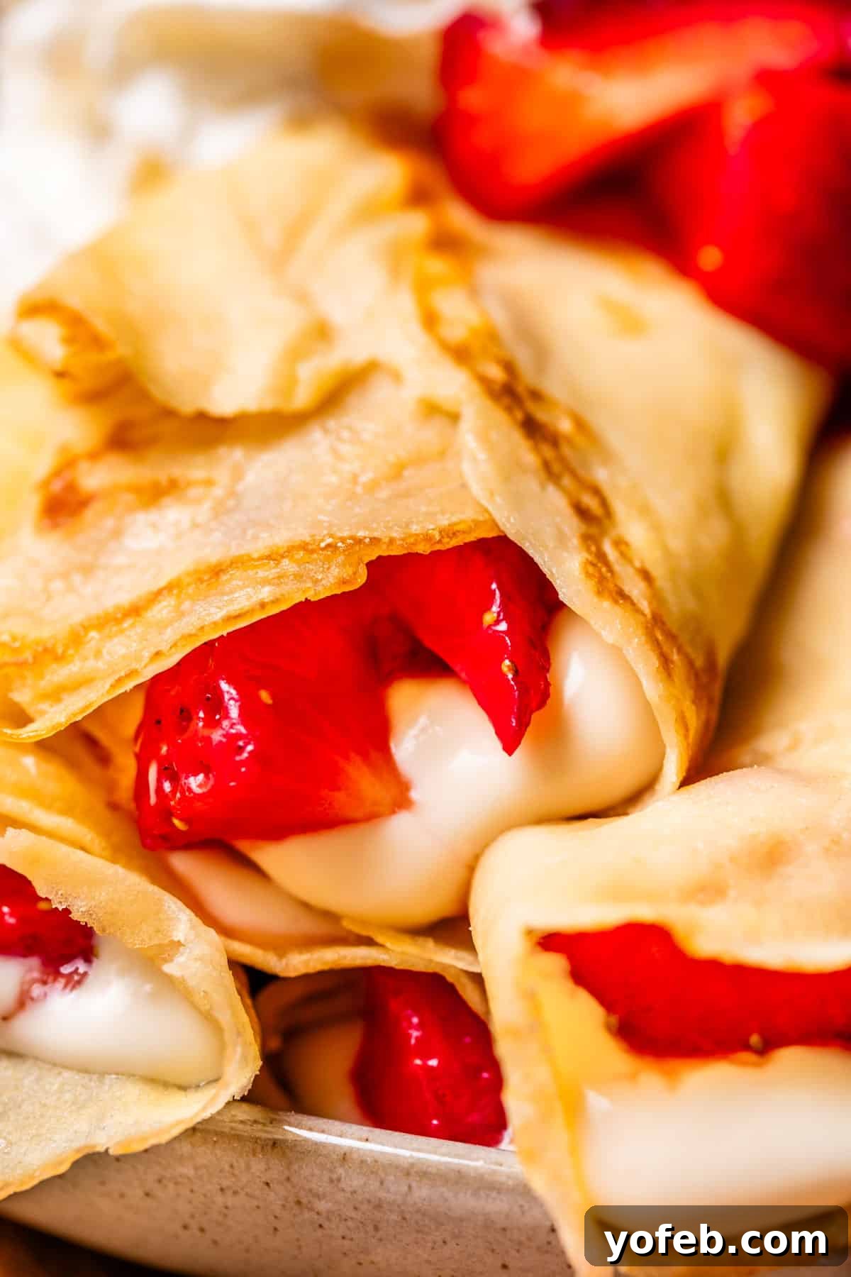 Absolutely The Best Crepes 26 A close-up view of a beautifully prepared crepe, generously stuffed with a creamy cream cheese spread and topped with vibrant strawberry compote, highlighting its appealing textures and colors.