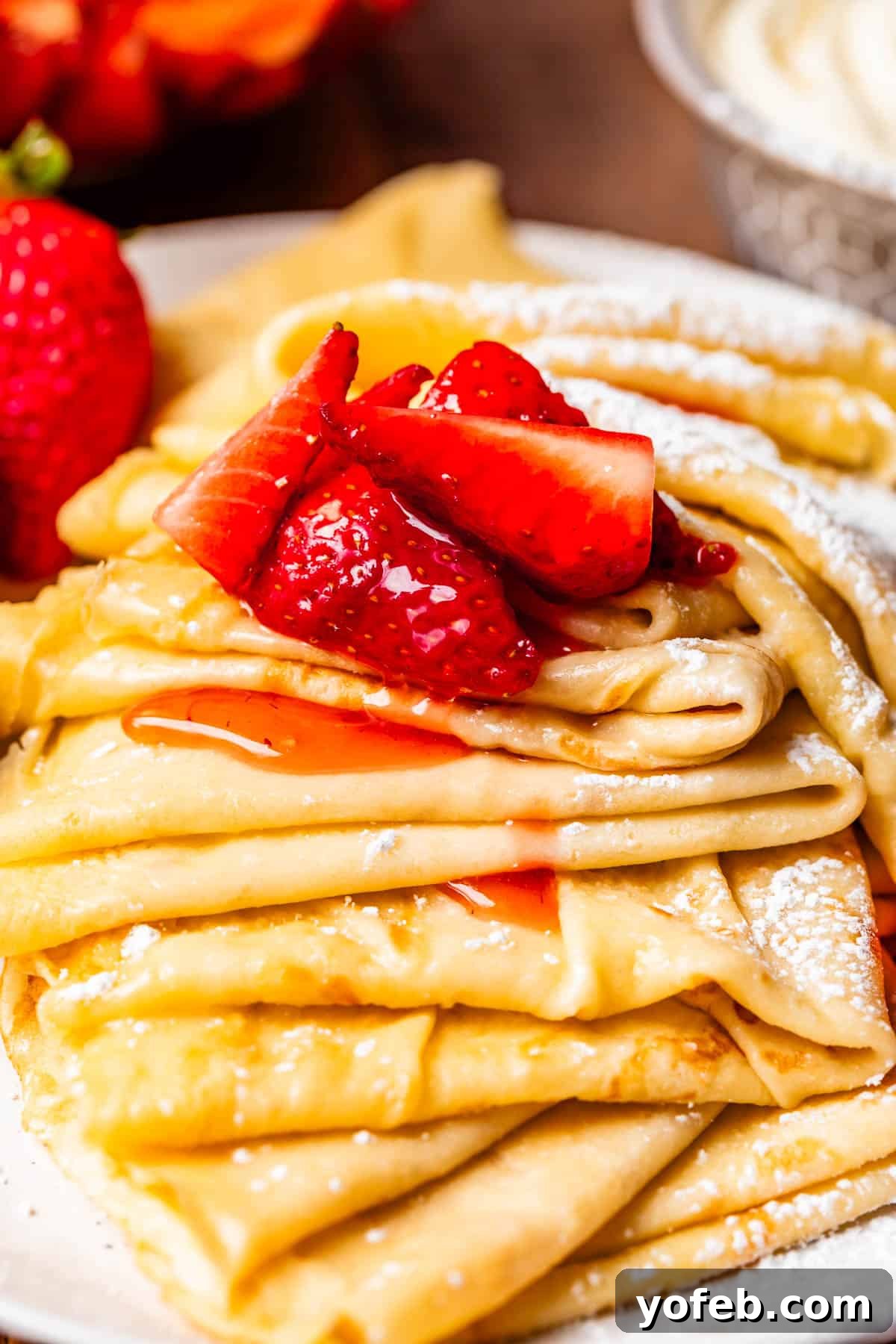 Absolutely The Best Crepes 4 Multiple delicate crepes, artfully folded and dusted with powdered sugar, served alongside a ladle overflowing with glistening macerated strawberries. A truly irresistible treat.