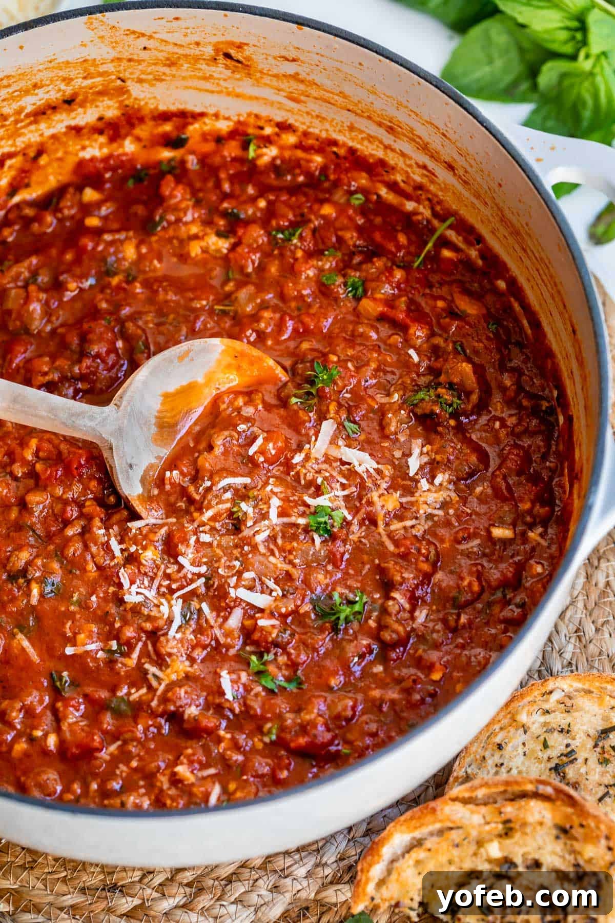 Effortless 30-Minute Spaghetti Sauce 12 A pristine white ceramic cooking pot filled with our rich, easy homemade spaghetti sauce, being gently stirred by a wooden spoon.