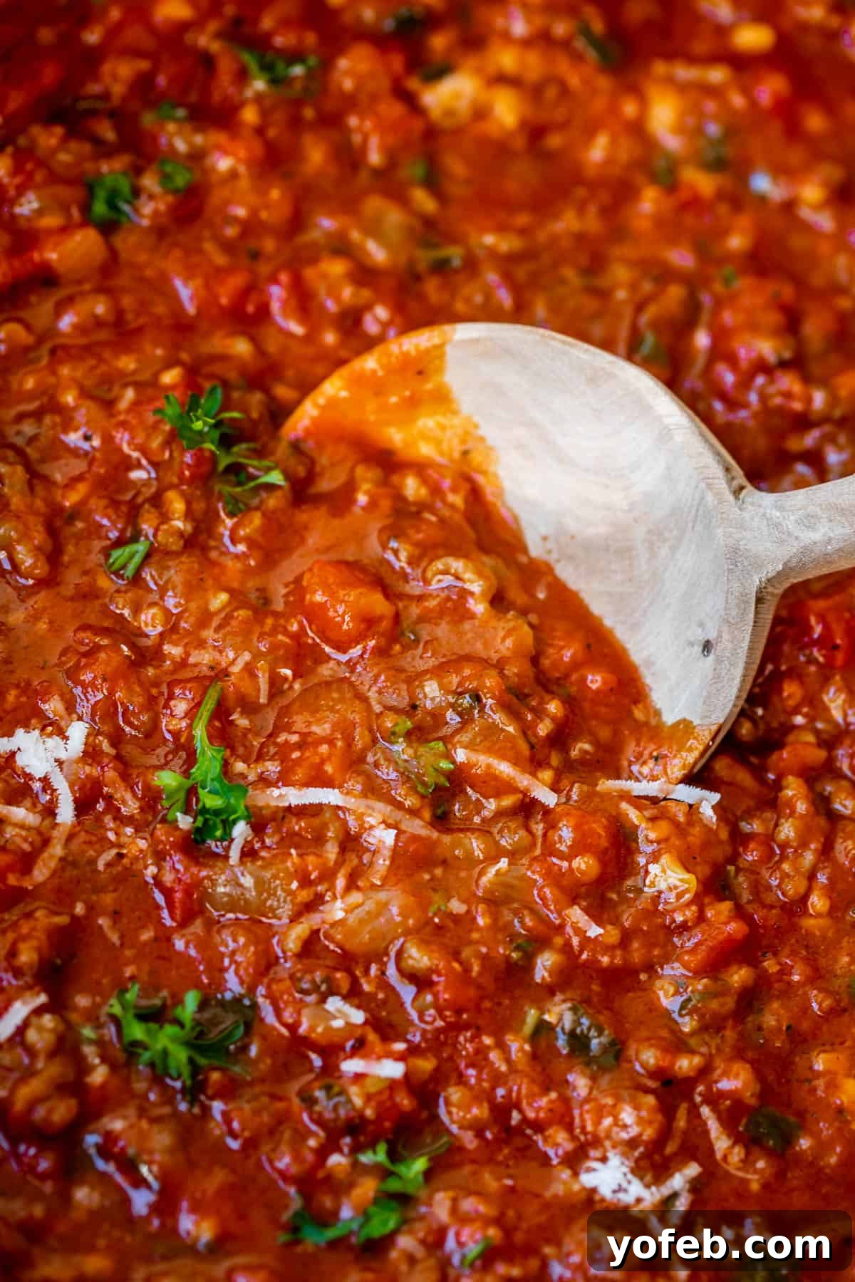 Effortless 30-Minute Spaghetti Sauce 15 A close-up of our velvety homemade spaghetti sauce, showing savory bits of onion, Italian sausage, grated Parmesan, and fresh basil.