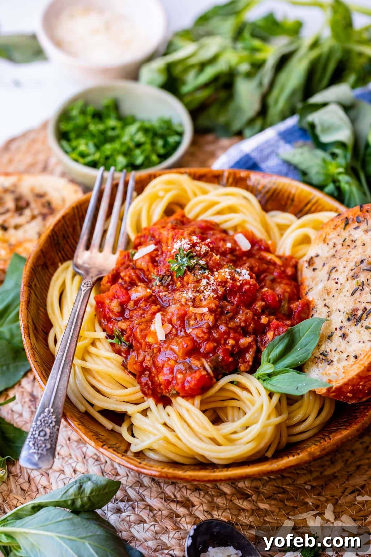 Effortless 30-Minute Spaghetti Sauce 3 A beautifully plated bowl of spaghetti noodles adorned with a rich, easy homemade sauce, accompanied by a fork and golden garlic bread on the side.